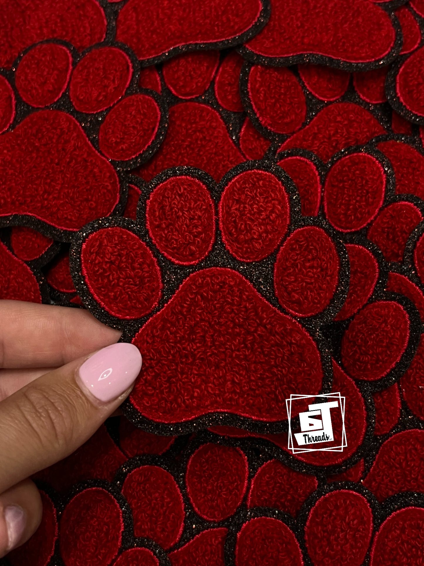 Red heart-shaped patches on a black background with a hand holding one patch.