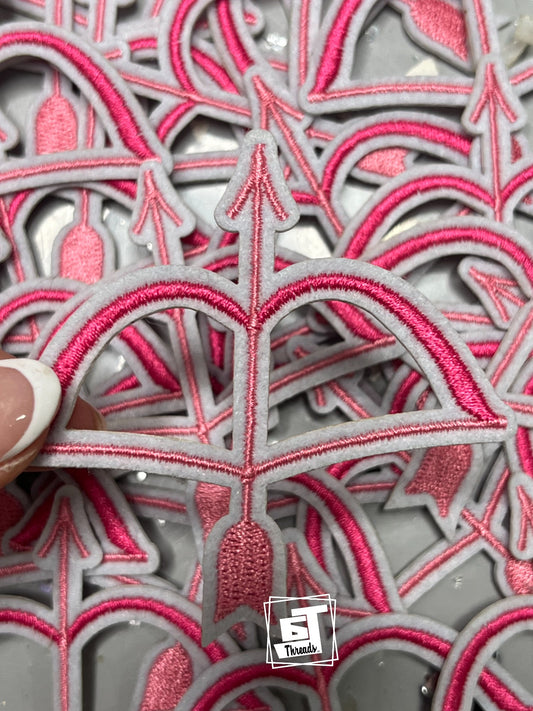 Stack of pink and gray embroidered patches with a visible brand logo in the corner.