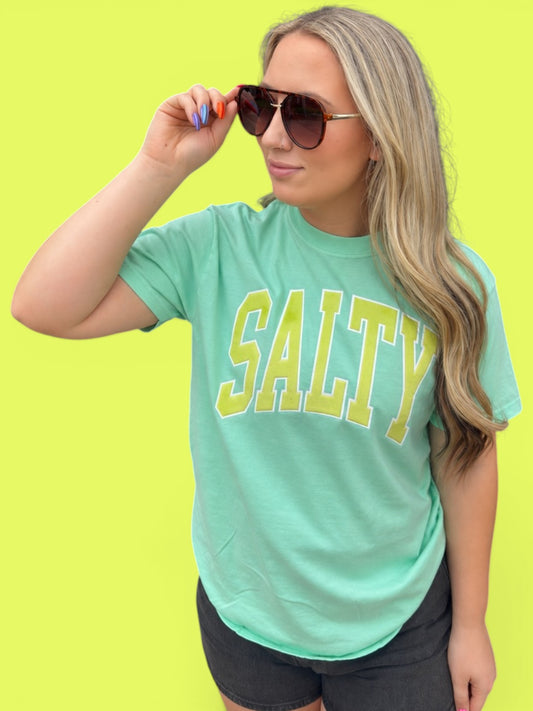Woman wearing a green 'SALTY' t-shirt against a bright yellow background