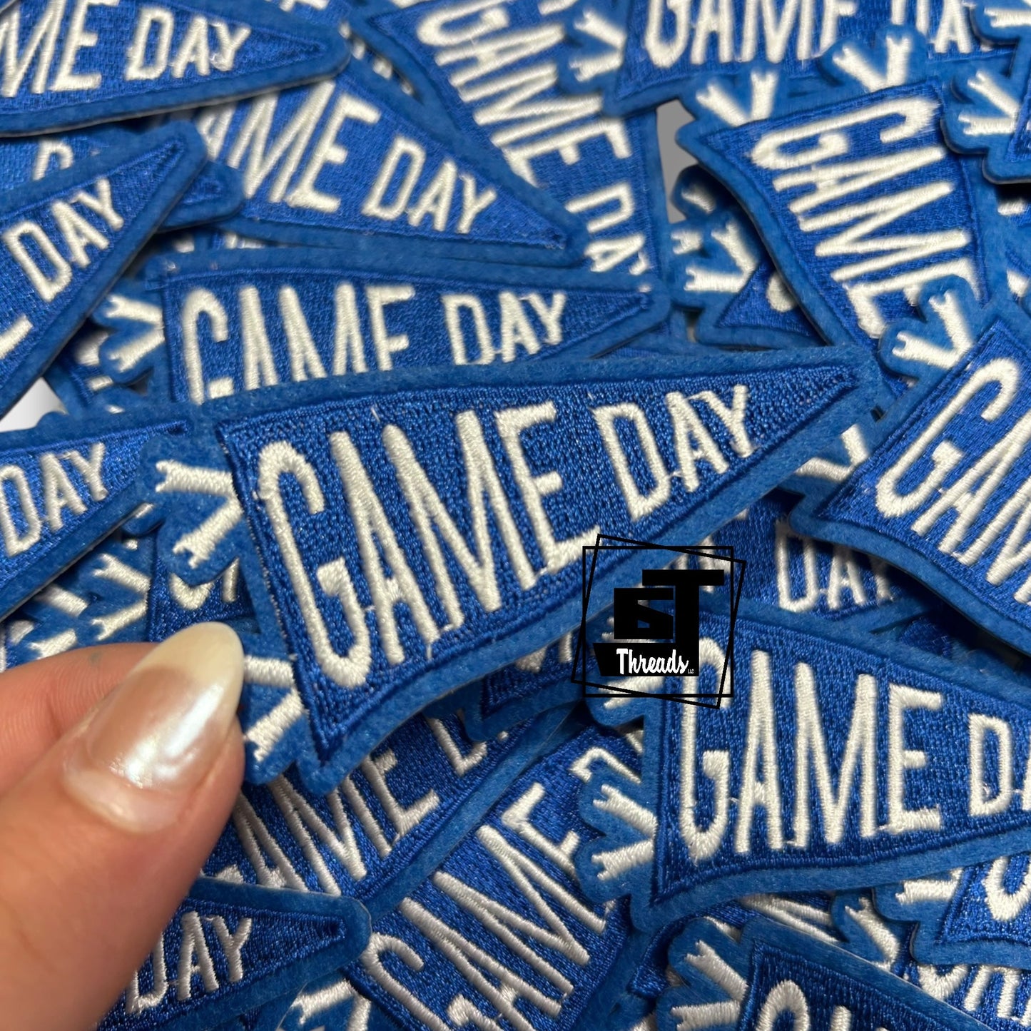 Blue patches with 'GAME DAY' text held by a hand, with a visible brand logo.