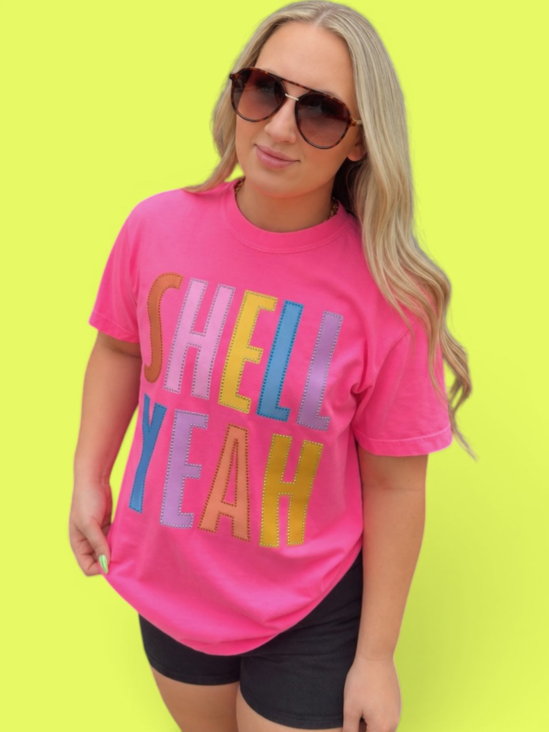 Woman wearing a pink t-shirt with colorful text on a bright yellow background