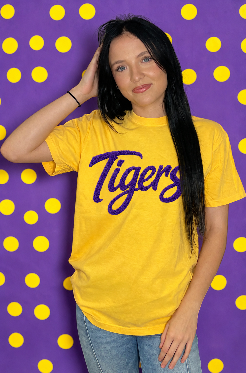 Woman wearing a yellow 'Tigers' t-shirt against a purple background with yellow polka dots