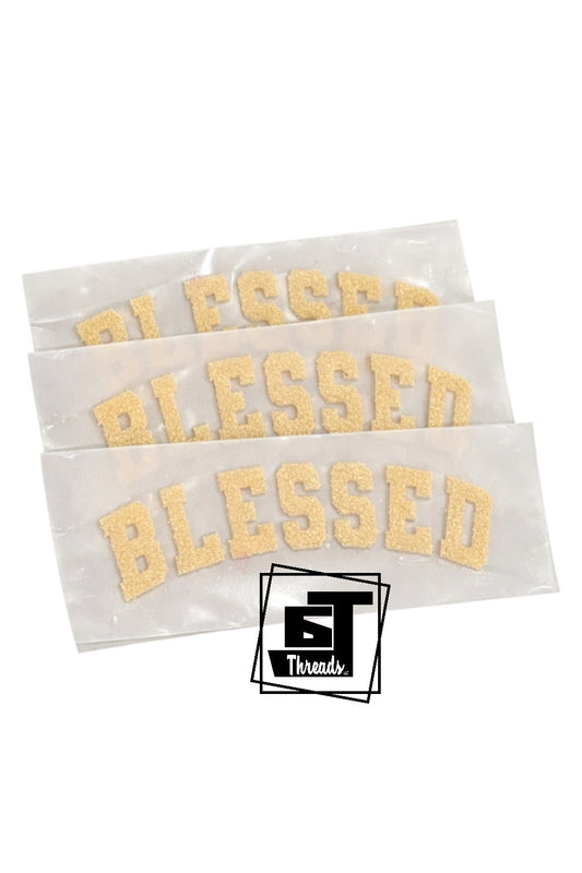 Three white paper strips with 'Blessed' printed in gold, featuring a logo in the corner.