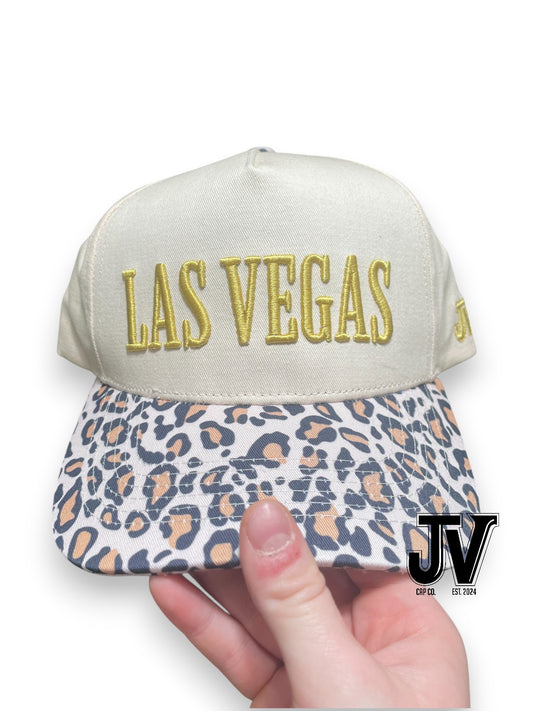 Cap with 'Las Vegas' text and leopard print visor held by a hand, with a visible brand logo.