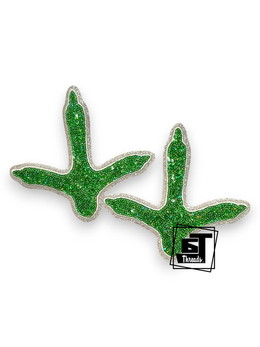 Green glittery antlers on a white background with a brand logo in the corner.