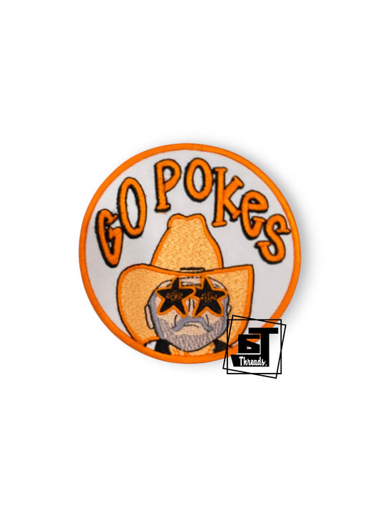 A circular embroidered patch featuring the text 'GO POKES' in orange above a cowboy hat with a bearded face wearing star-shaped glasses. A small 'GT Threads' logo is overlaid near the bottom right of the patch.
