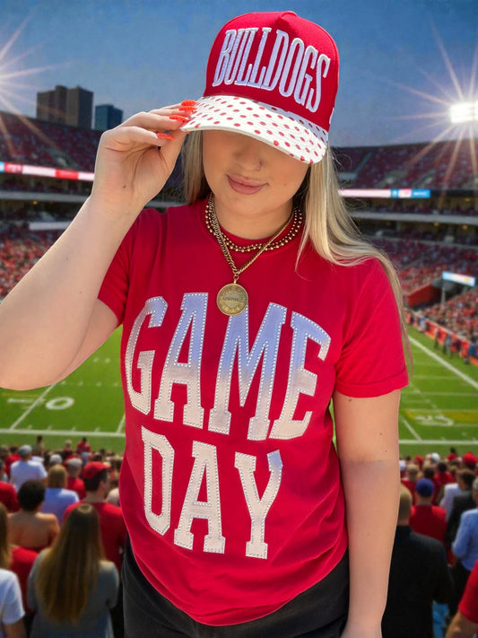 Person wearing a red 'Bulldogs' cap and 'Game Day' shirt at a sports event.