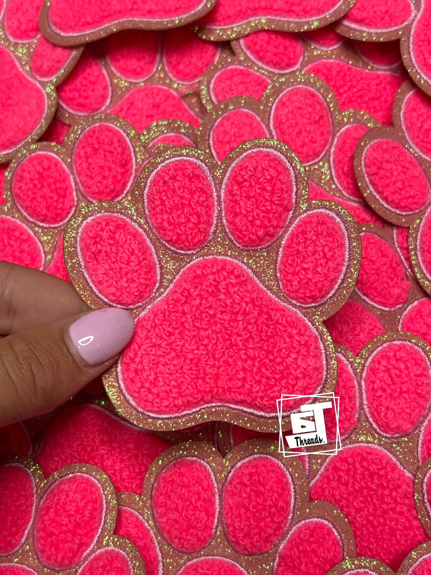Pink textured heart-shaped objects with gold border held by a hand, brand logo visible.