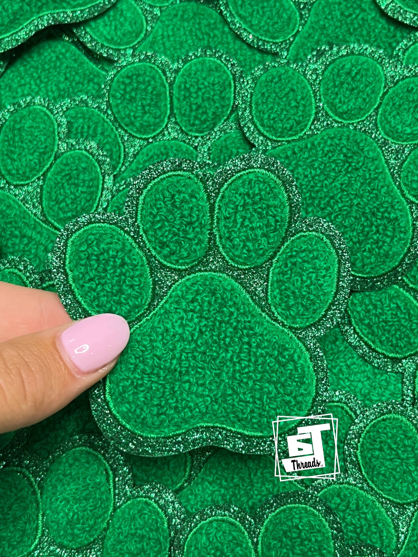 Green textured patch with a paw print design held by a hand, branded 'ST Trends'.