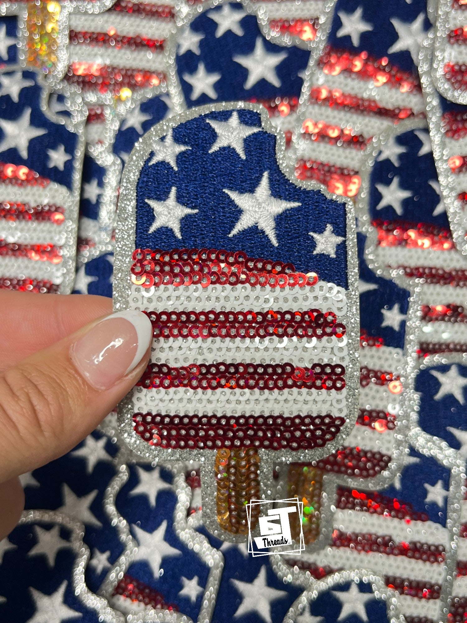 Decorative item with American flag design and rhinestones, held by a hand.