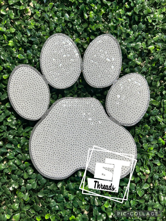 Gray paw print design on grass with 'Threads' logo in corner