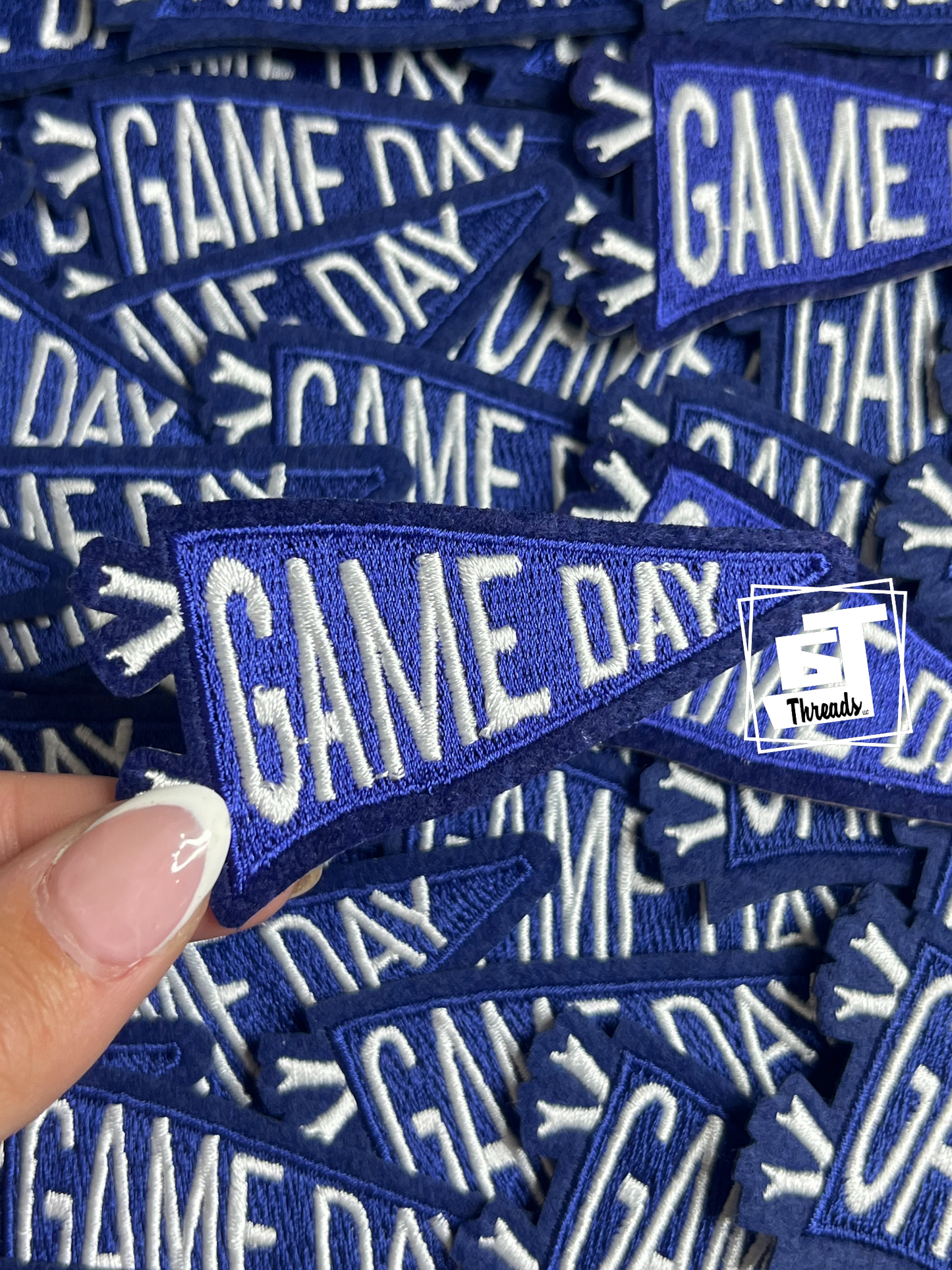 Blue and white 'GAME DAY' patches with a hand holding one patch.