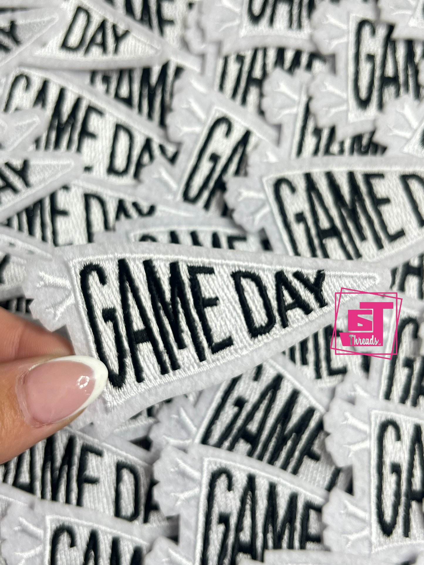 white Collection of 'GAME DAY' patches with a hand holding one patch.