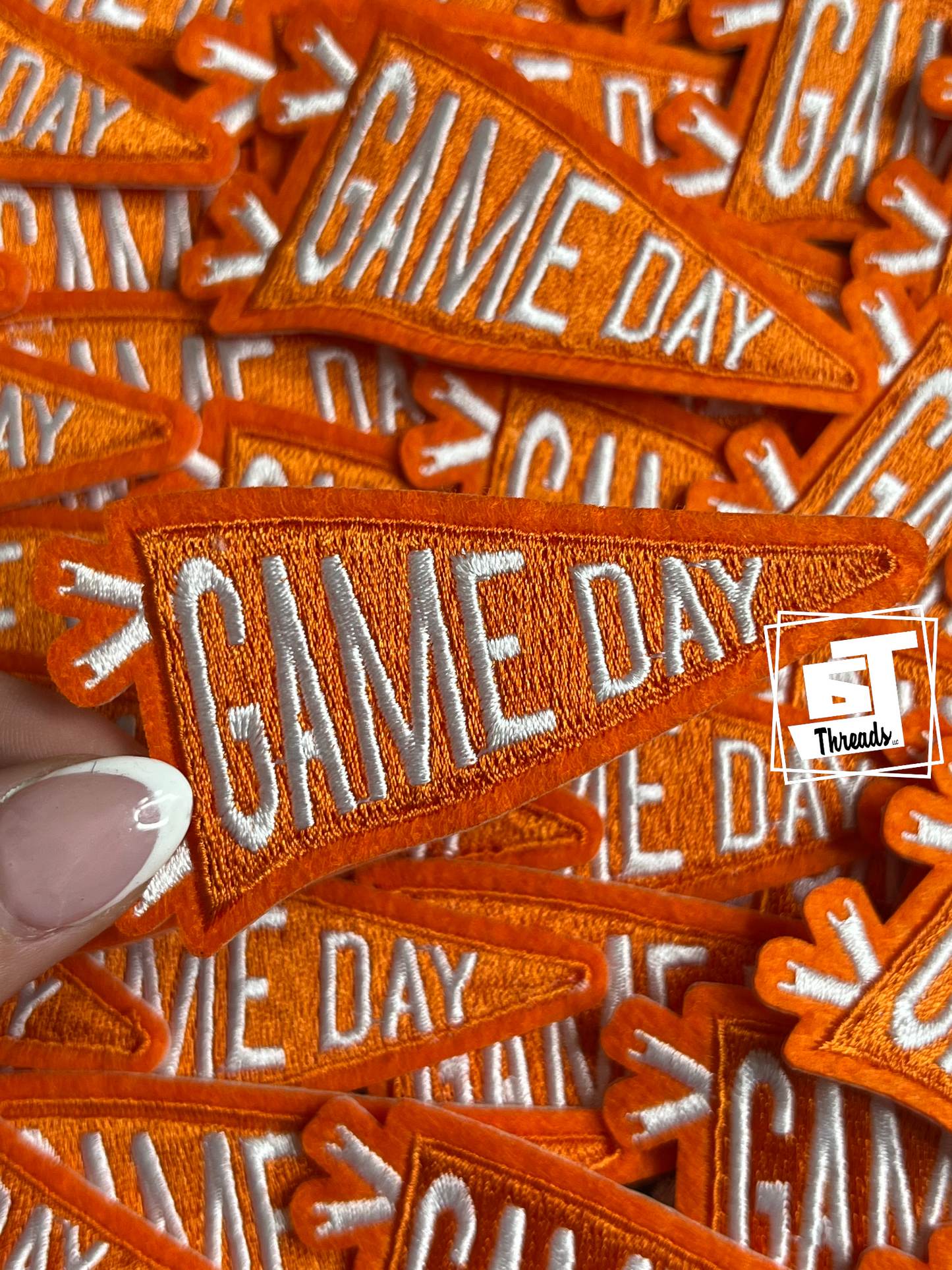 Collection of orange 'GAME DAY' patches with a visible brand logo.