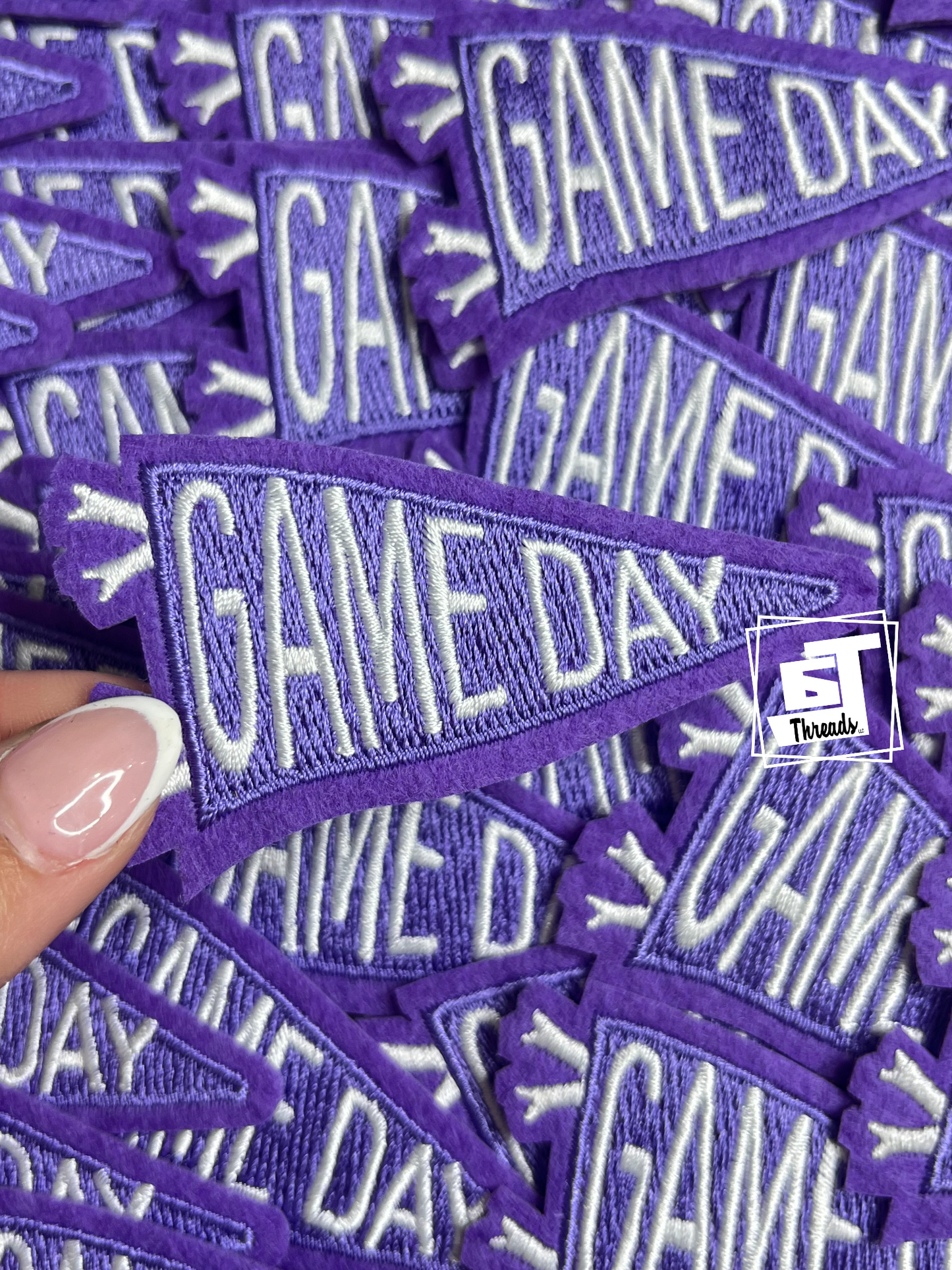 Purple 'GAME DAY' patches with a hand holding one patch.