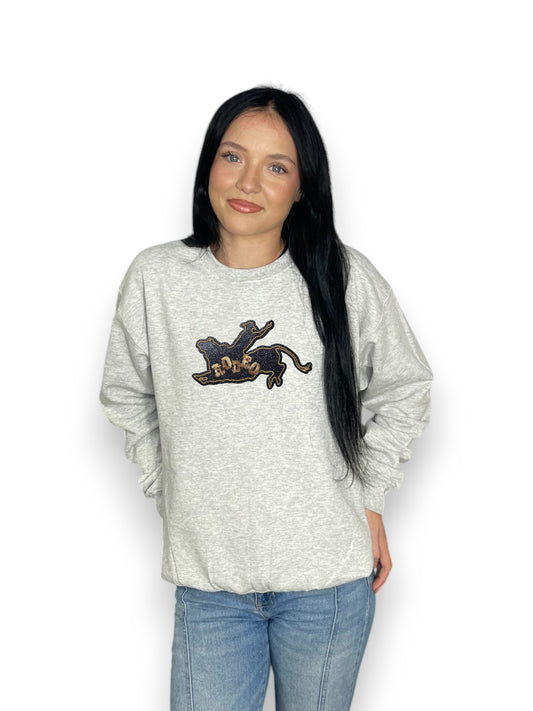 Person wearing a gray sweatshirt with a black and gold design on a white background