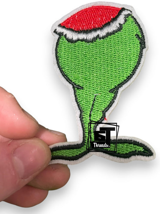 Green and red Grinch patch held by a hand on a white background