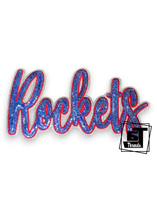 Measurements 11 inches wide by 6 inches tall
Blue and red cursive sequin rockets with red embroidery and silver glitter background
Iron-on Patch