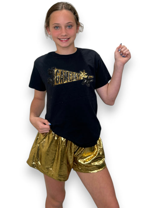 Person wearing a black t-shirt with gold text and gold shorts on a white background