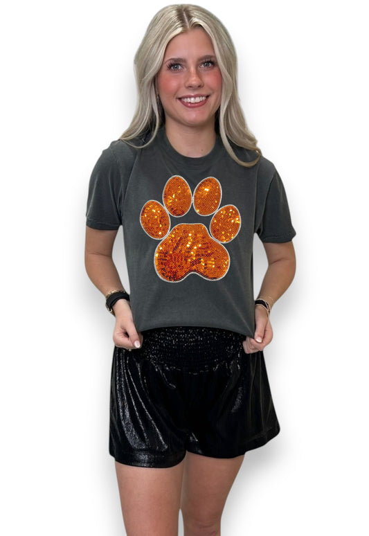 Woman wearing a dark gray t-shirt with an orange paw print design on a white background