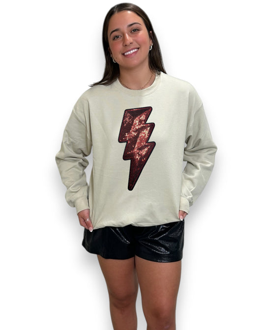 Woman wearing a light-colored sweatshirt with a sequin lightning bolt design on a white background