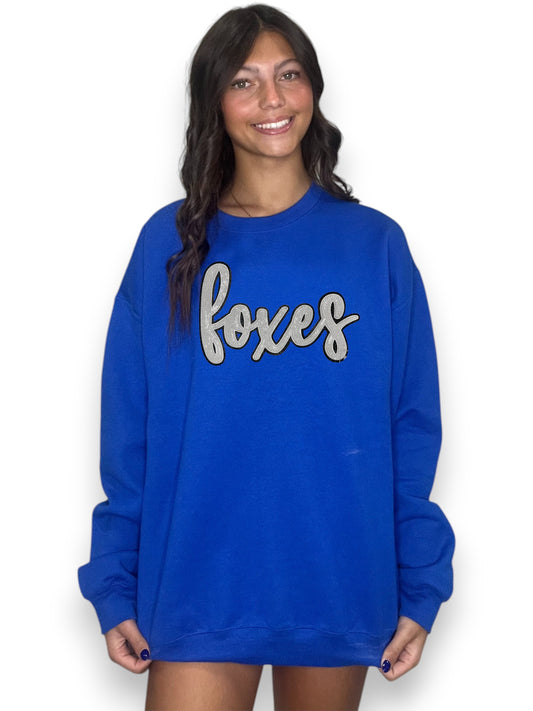 Woman wearing a blue sweatshirt with 'foxes' text on a white background