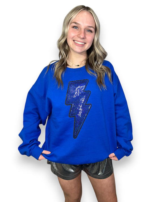 Person wearing a blue sweatshirt with a lightning bolt design on a white background