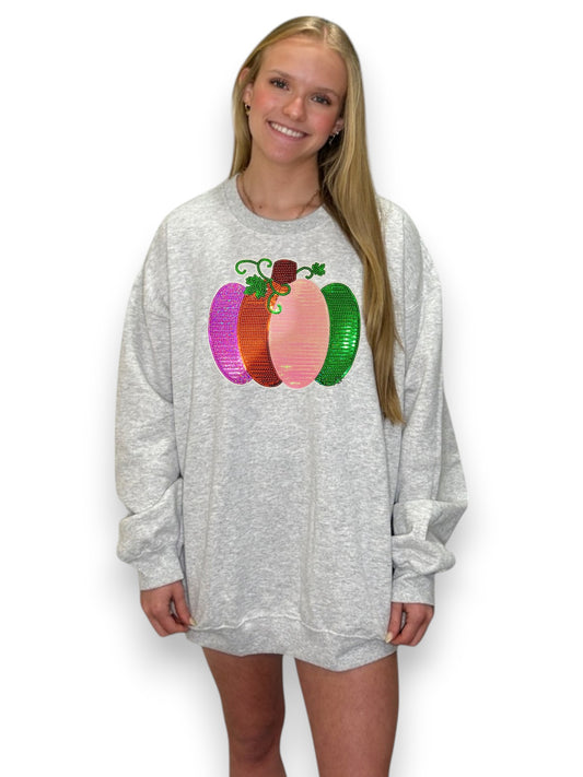 Person wearing a gray sweatshirt with colorful pumpkin design on a white background