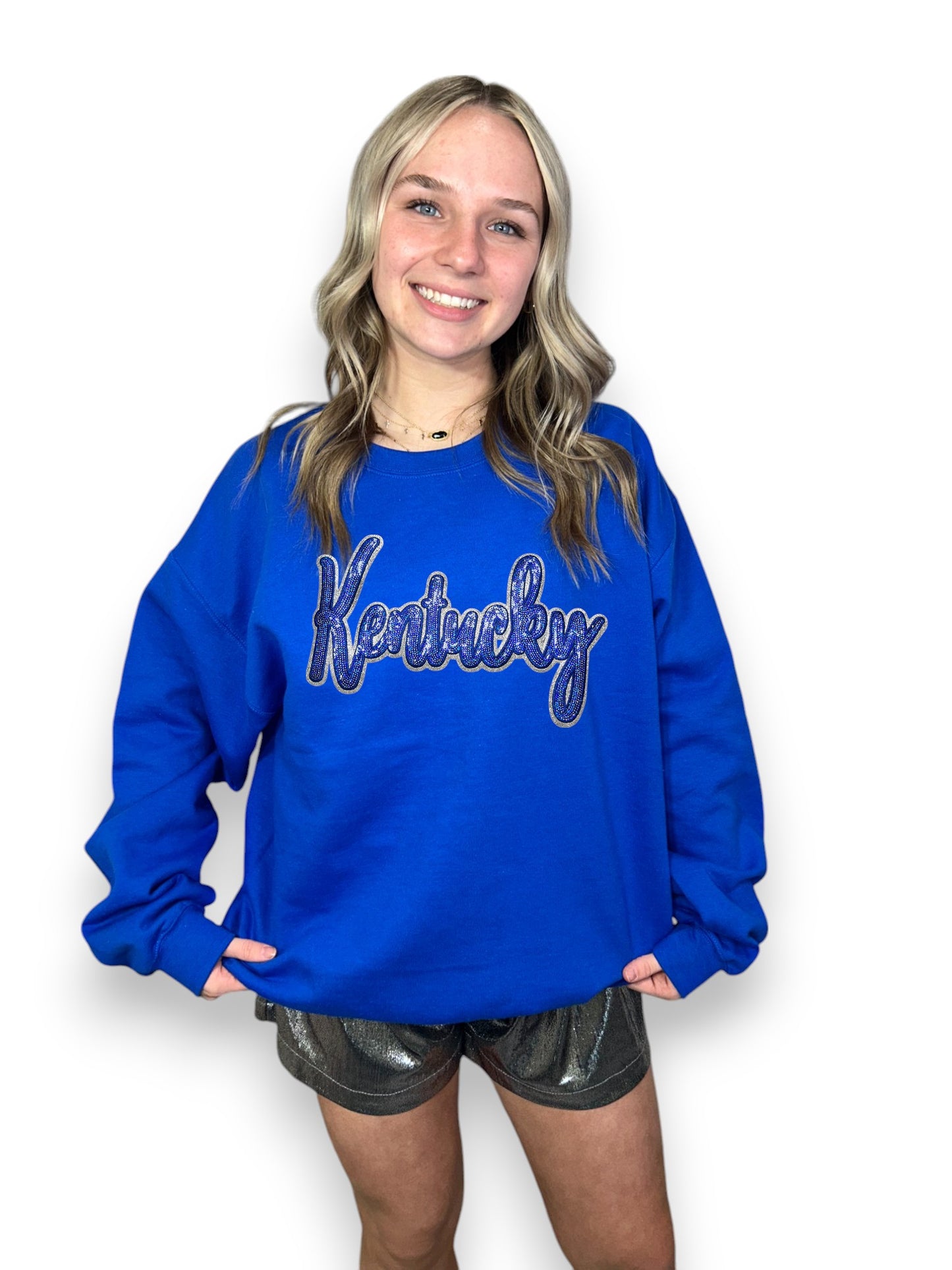 Person wearing a blue 'Kentucky' sweatshirt on a white background