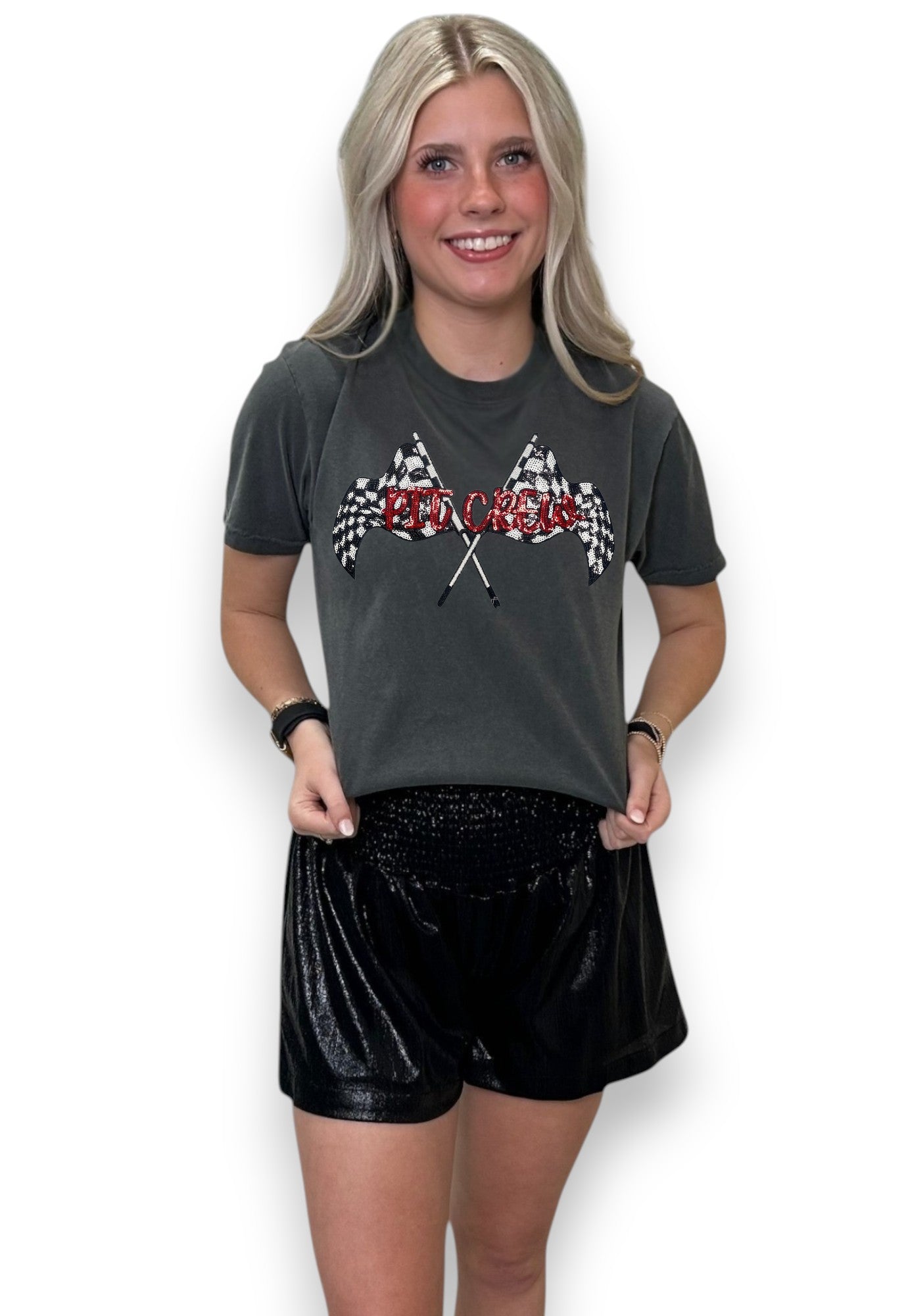 Woman wearing a dark gray t-shirt with racing flag design and black shorts on a white background