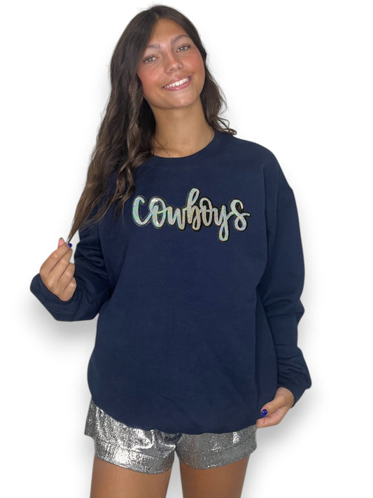 Woman wearing a navy sweatshirt with 'Cowboys' text and silver shorts on a white background