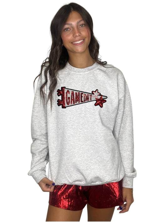 Person wearing a gray sweatshirt with 'GAMEDAY' design and red shorts on a white background