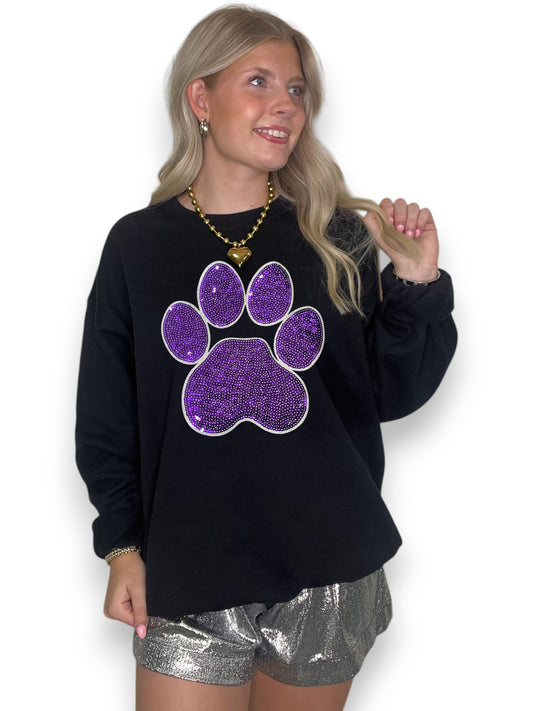 Woman wearing a black sweatshirt with a purple paw print design on a white background