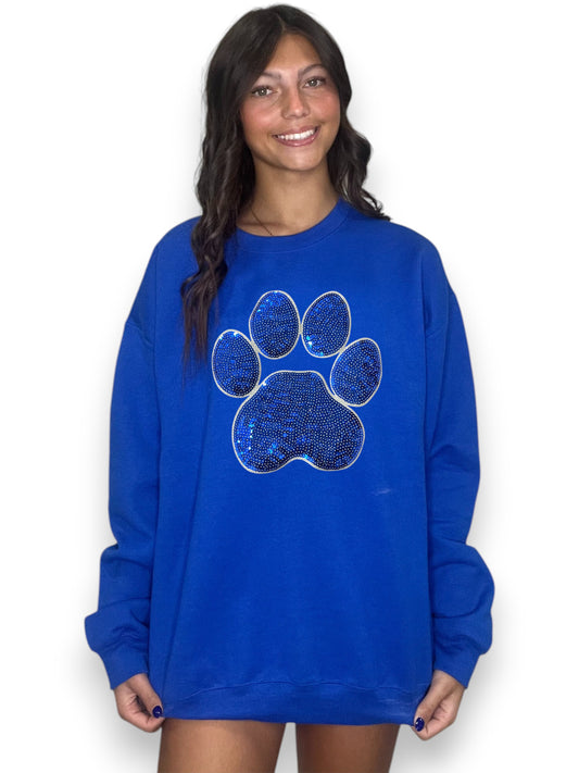 Woman wearing a blue sweatshirt with a paw print design on a white background