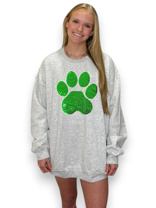 Person wearing a gray sweatshirt with a green paw print design on a white background