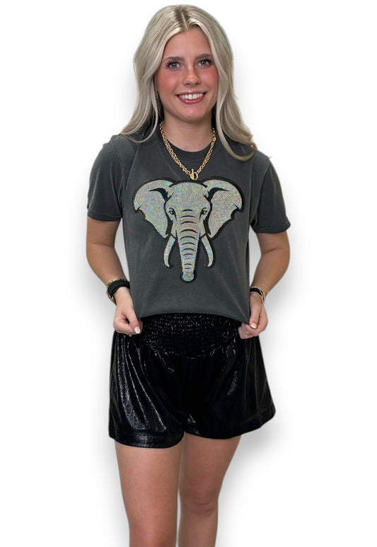 Woman wearing a dark gray t-shirt with an elephant graphic and black shorts on a white background