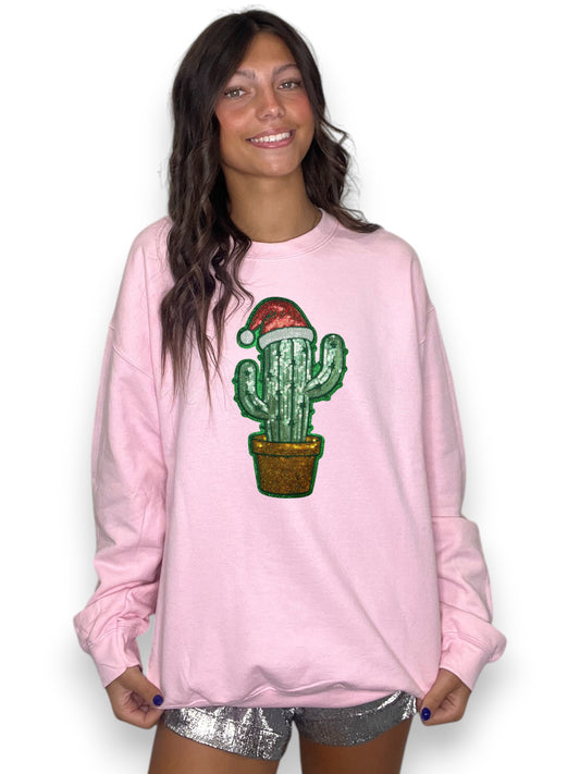 Person wearing a pink sweatshirt with a cactus graphic and Santa hat on a white background