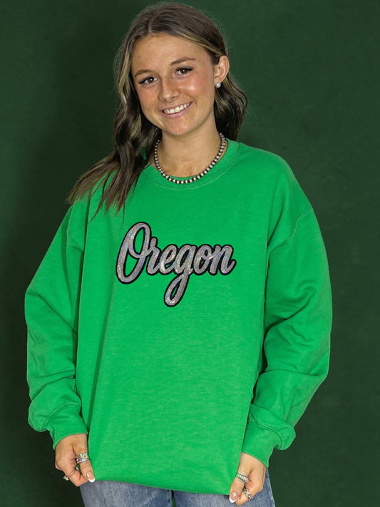 Person wearing a green sweatshirt with 'Oregon' text on a dark green background