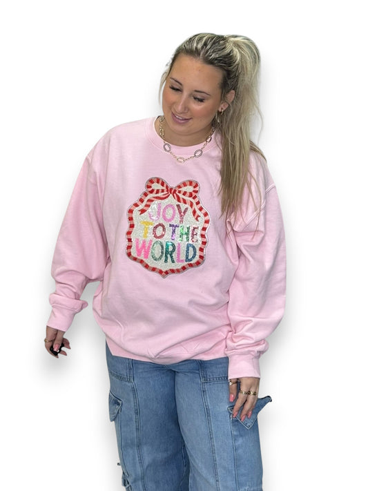 Person wearing a pink sweatshirt with 'Joy to the World' design on a white background