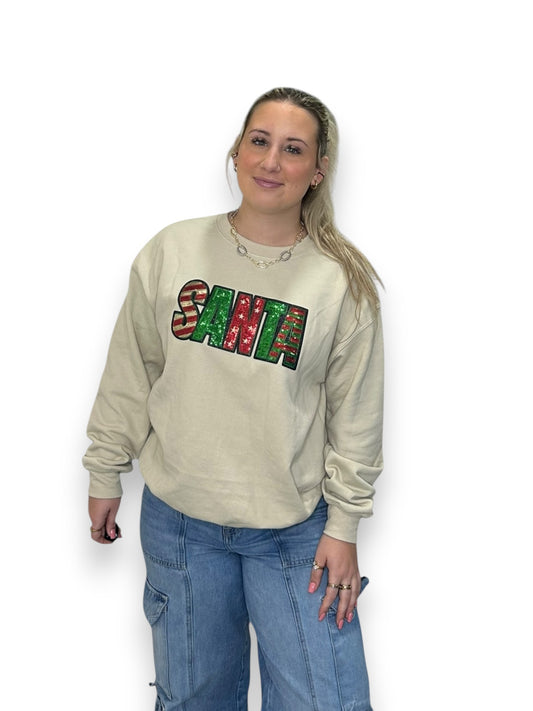 Woman wearing a beige sweatshirt with colorful 'SANTA' text on a white background