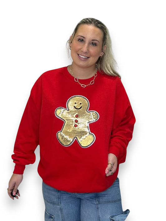 Person wearing a red sweatshirt with a gold gingerbread man design on a white background
