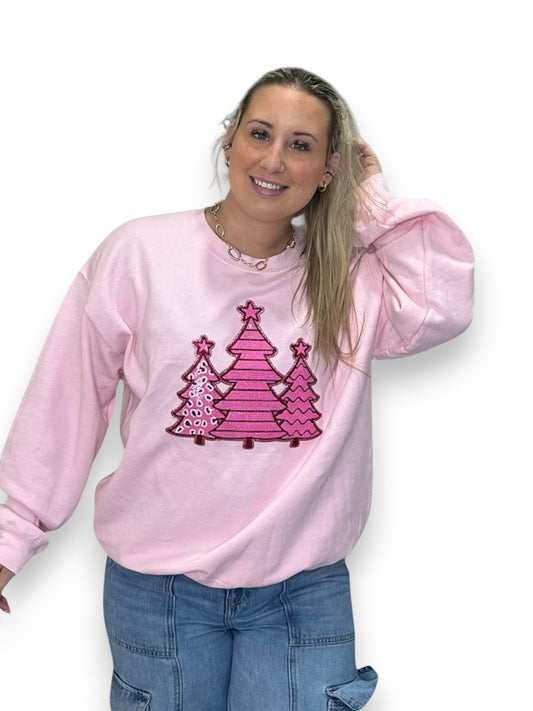 Woman wearing a pink sweatshirt with a Christmas tree design on a white background