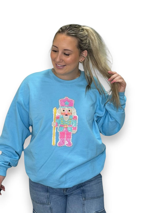 Person wearing a blue sweatshirt with a colorful graphic design on a white background