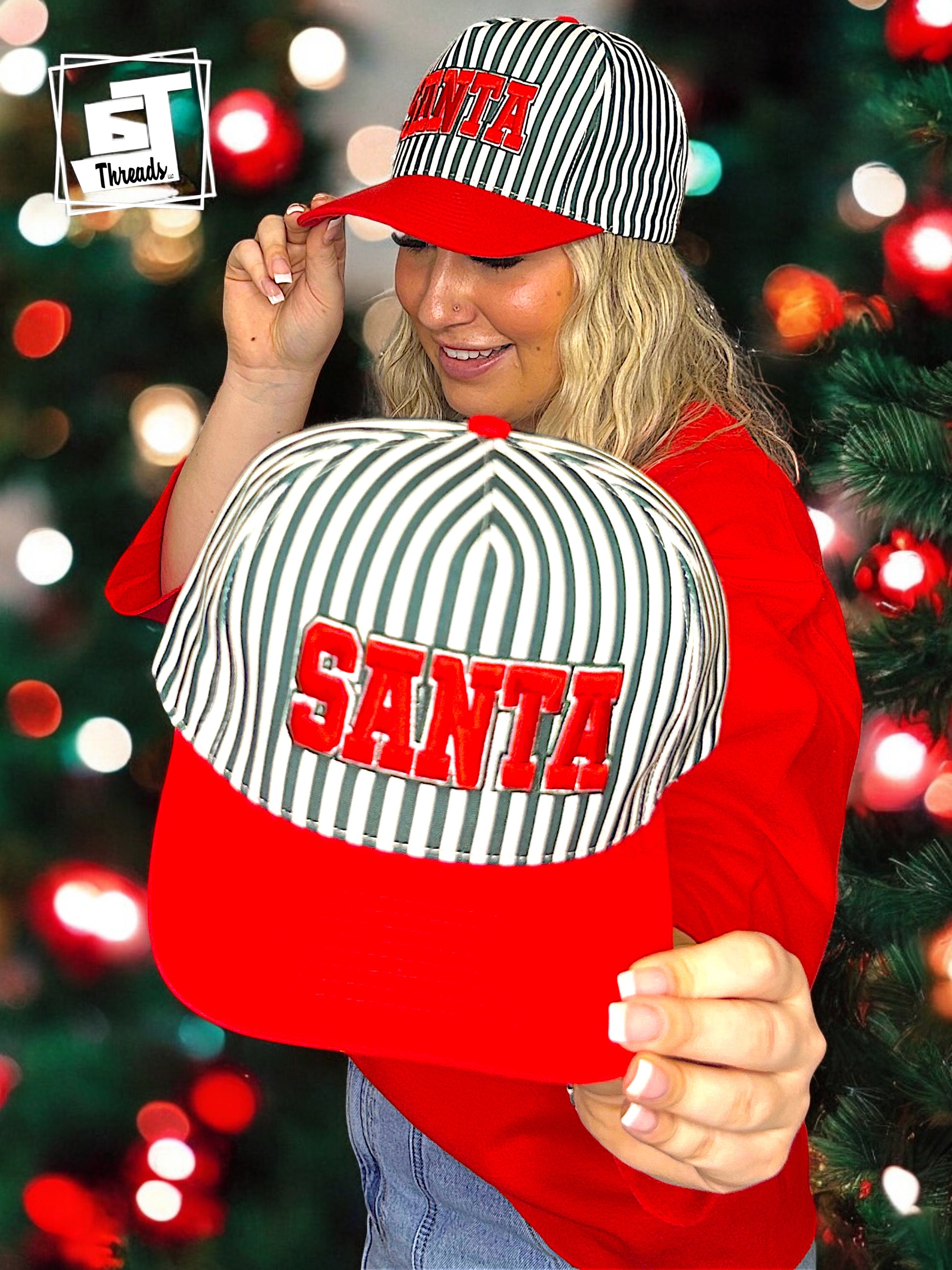 Santa cap with green and white stripe 6j threads girls stand holding a cap in front of a light with Christmas tree 