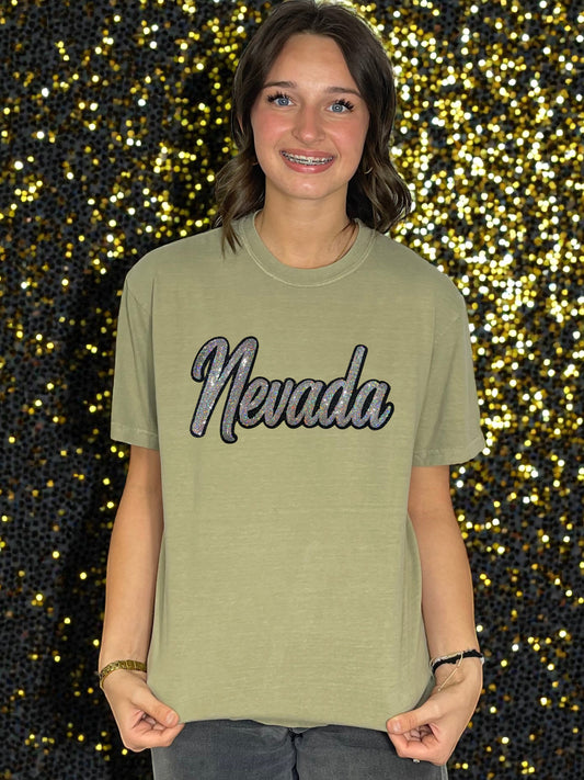 Person wearing a green t-shirt with 'Nevada' text against a glittery background
