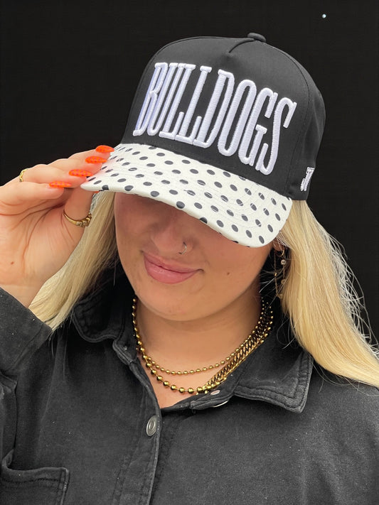Person wearing a black cap with 'BULLDOGS' text and a polka dot visor.