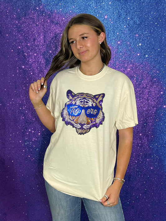 Person wearing a cream t-shirt with a purple tiger logo against a starry space background